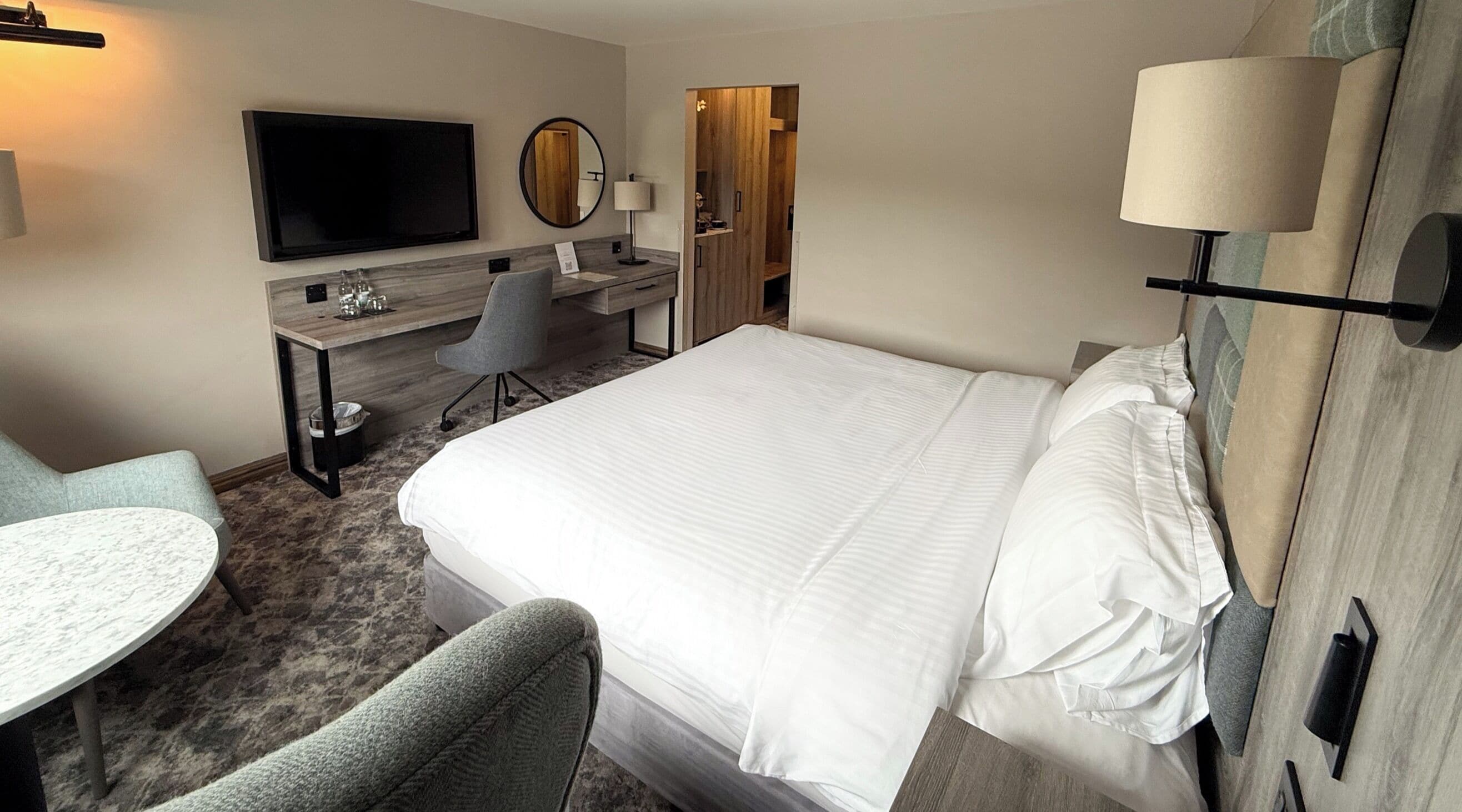 Ein Hotelzimmer mit Bett, Schreibtisch, Stuhl, Fernseher und Lampe.