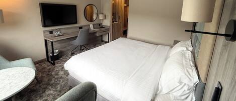 Ein Hotelzimmer mit Bett, Schreibtisch, Stuhl, Fernseher und Lampe.