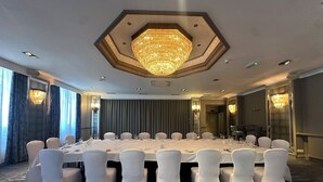 A conference room with a large round table, white chairs, and a central chandelier. - The Cabarfeidh Hotel (Stornoway)