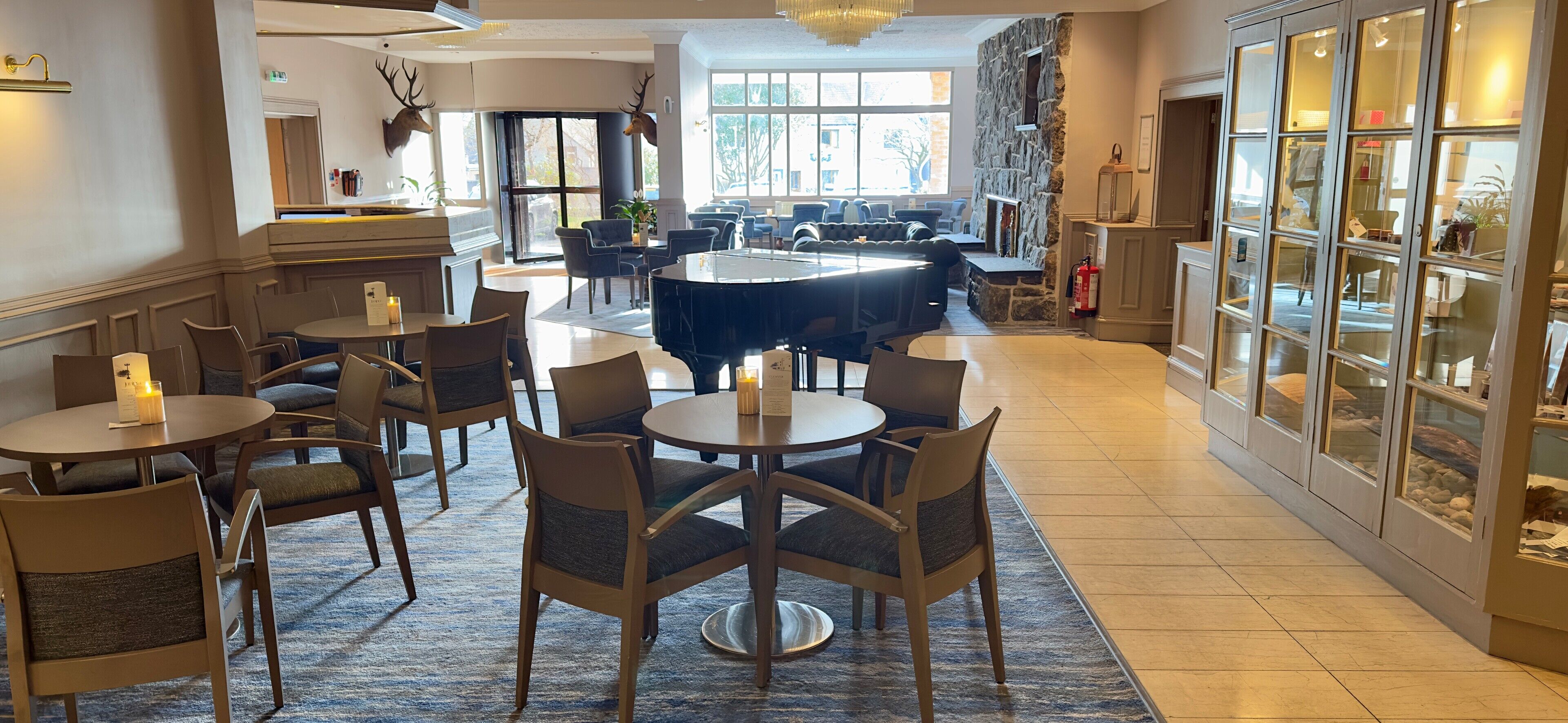 A spacious lobby with a grand piano, comfortable seating, and a stone fireplace.