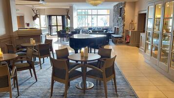 A spacious lobby with a grand piano, comfortable seating, and a stone fireplace.