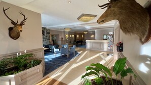 A spacious lobby with a grand piano, plush seating, and a reception desk. - The Cabarfeidh Hotel (Stornoway)
