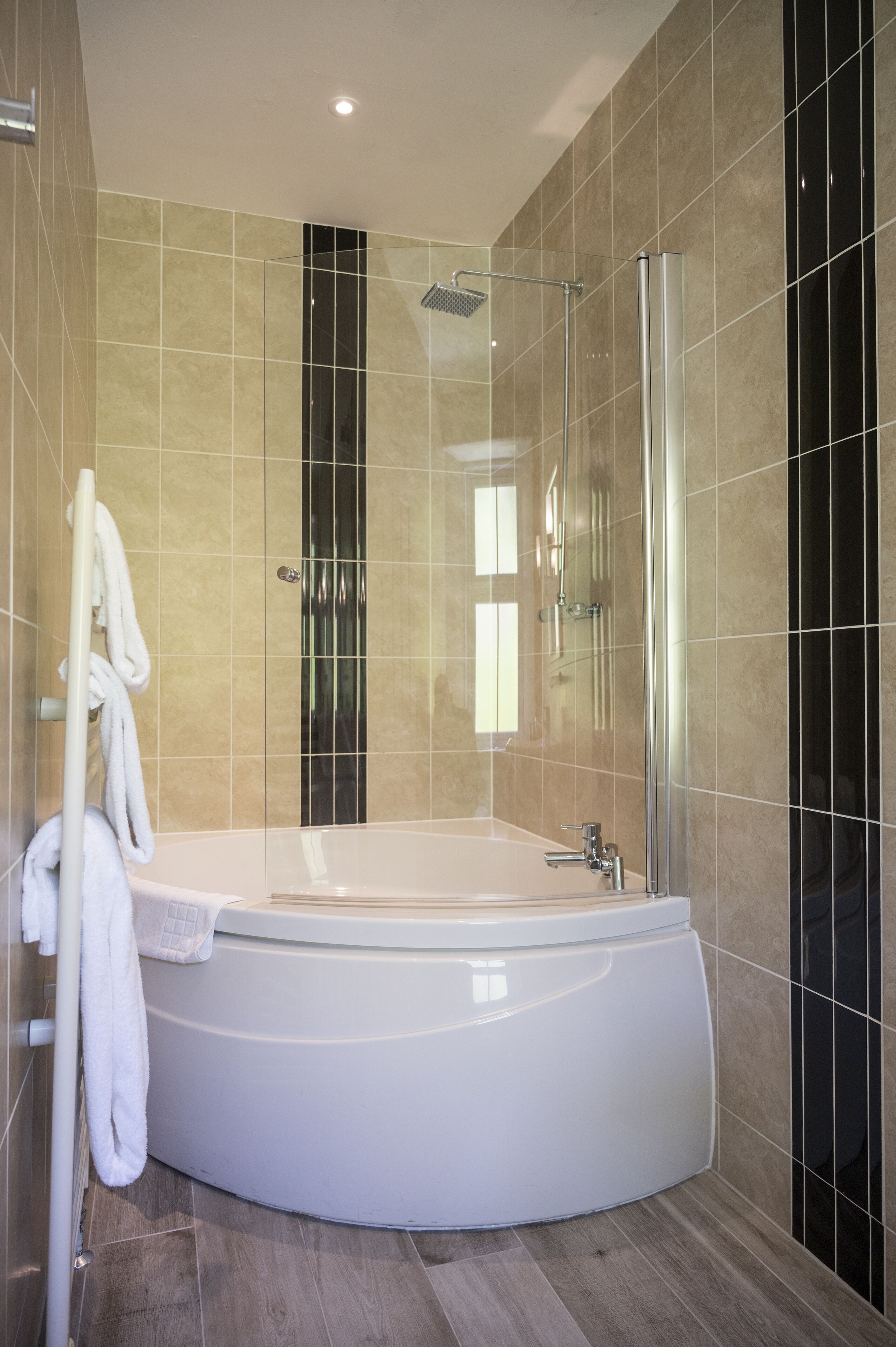 Un baño moderno con una bañera independiente, una ducha con cerramiento de vidrio y un perchero para toallas.