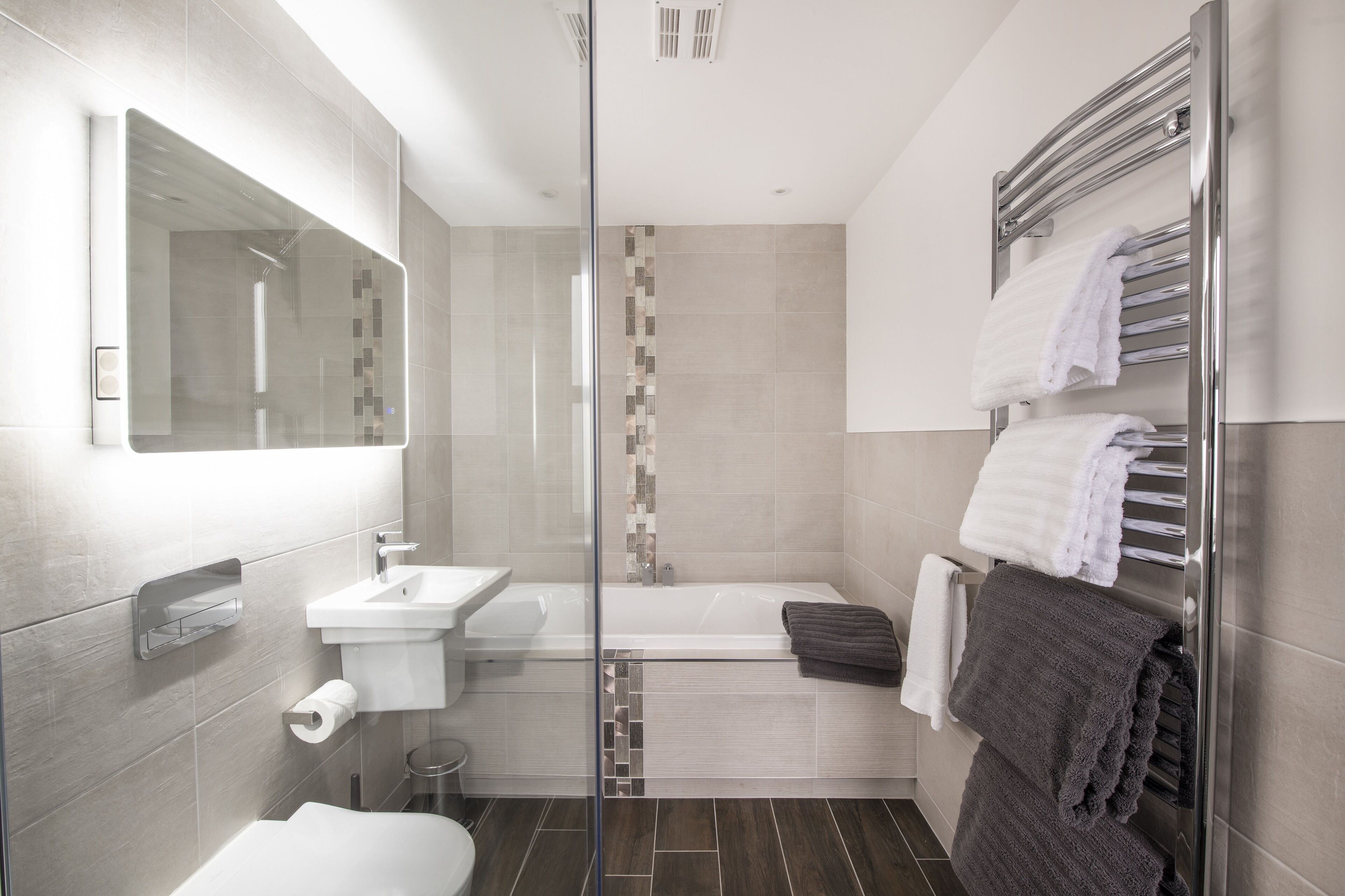 A modern bathroom with a glass shower enclosure, a white sink, and a bathtub.