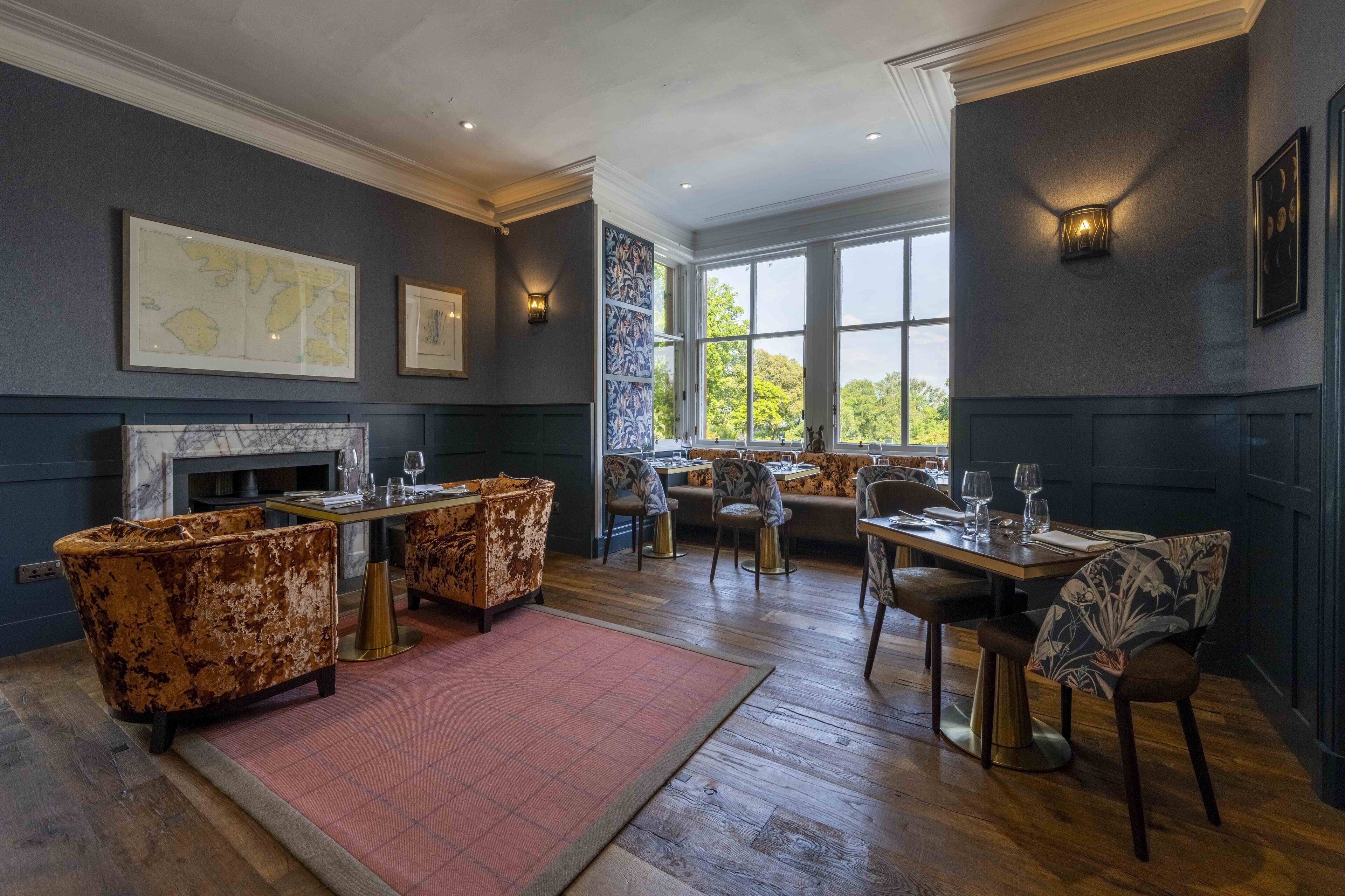 A dining area with a fireplace, seating, and artwork on the walls.