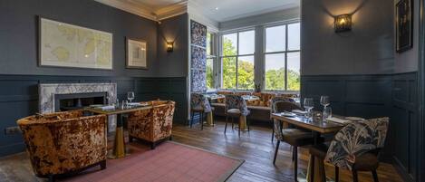 A dining area with a fireplace, seating, and artwork on the walls.
