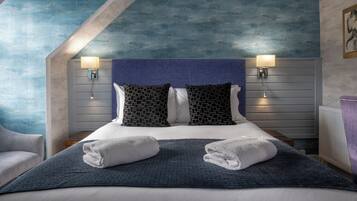 A hotel room with a bed, two wall-mounted lamps, and a blue textured ceiling.