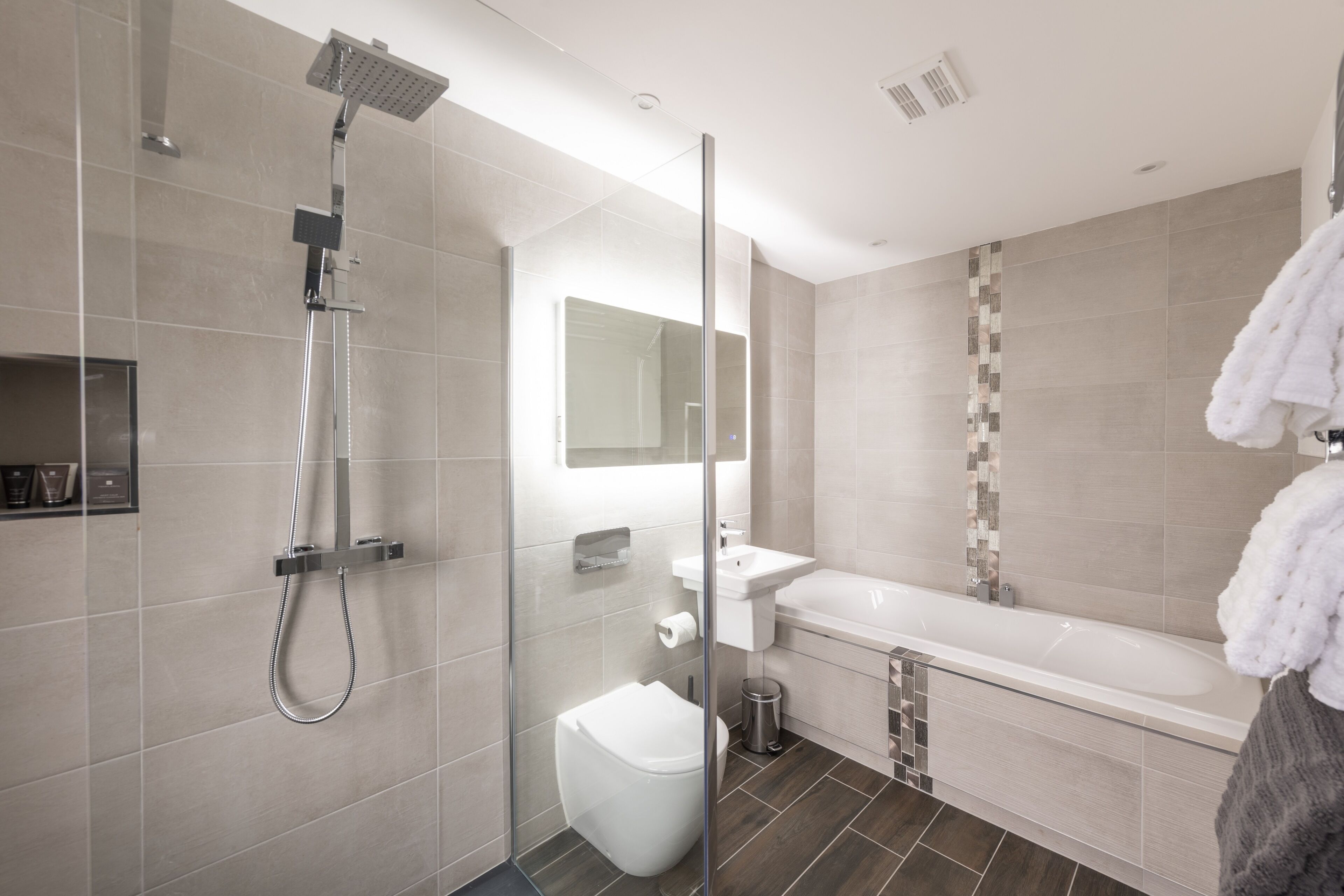 A modern bathroom with a glass-enclosed shower, a white toilet, a sink, and a bathtub.