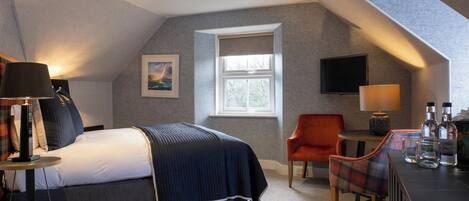 A modern bedroom with a bed, a desk, a chair, a TV, and a window.