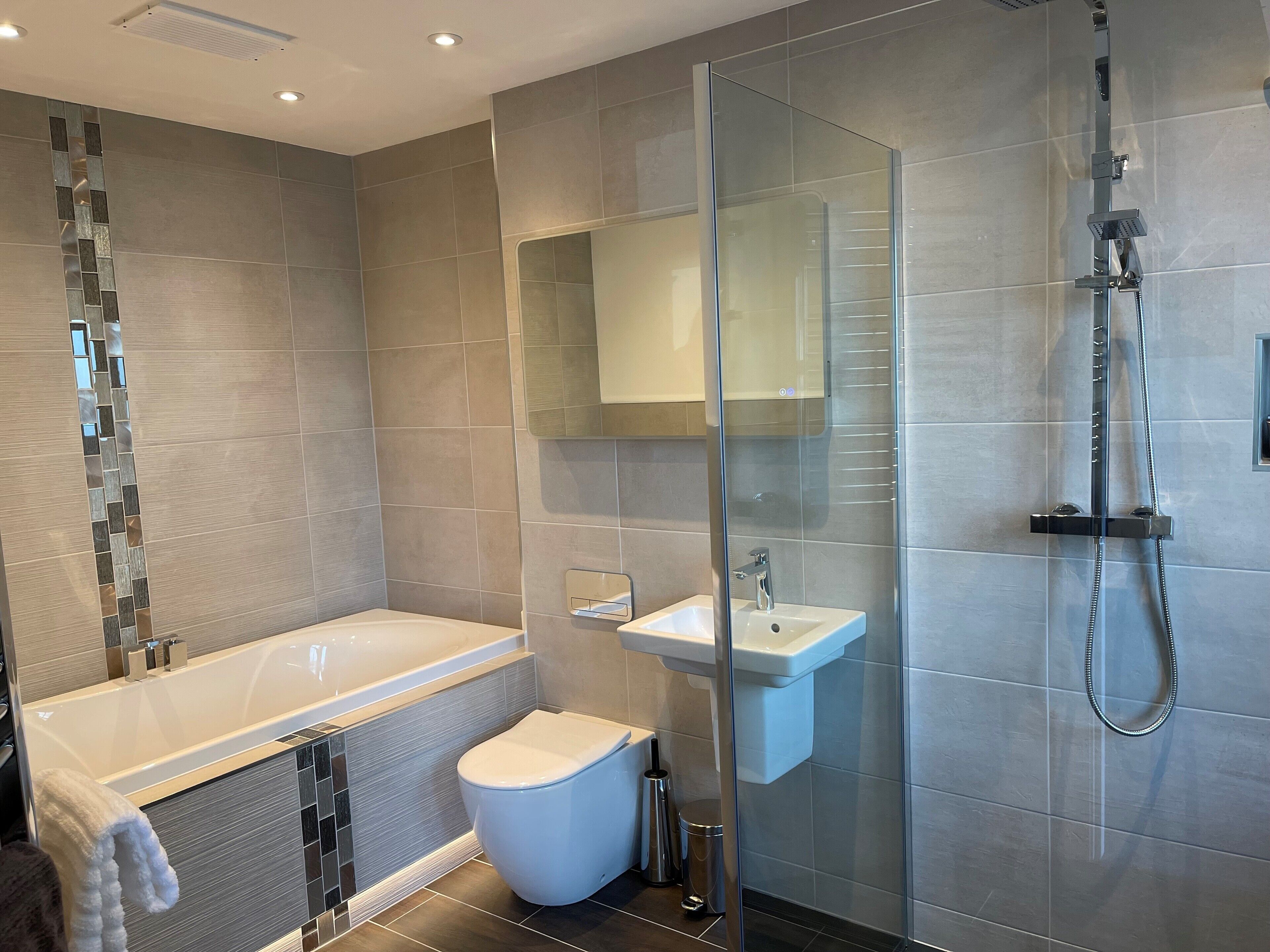 A modern bathroom with a glass-enclosed shower, a white bathtub, and a pedestal sink.