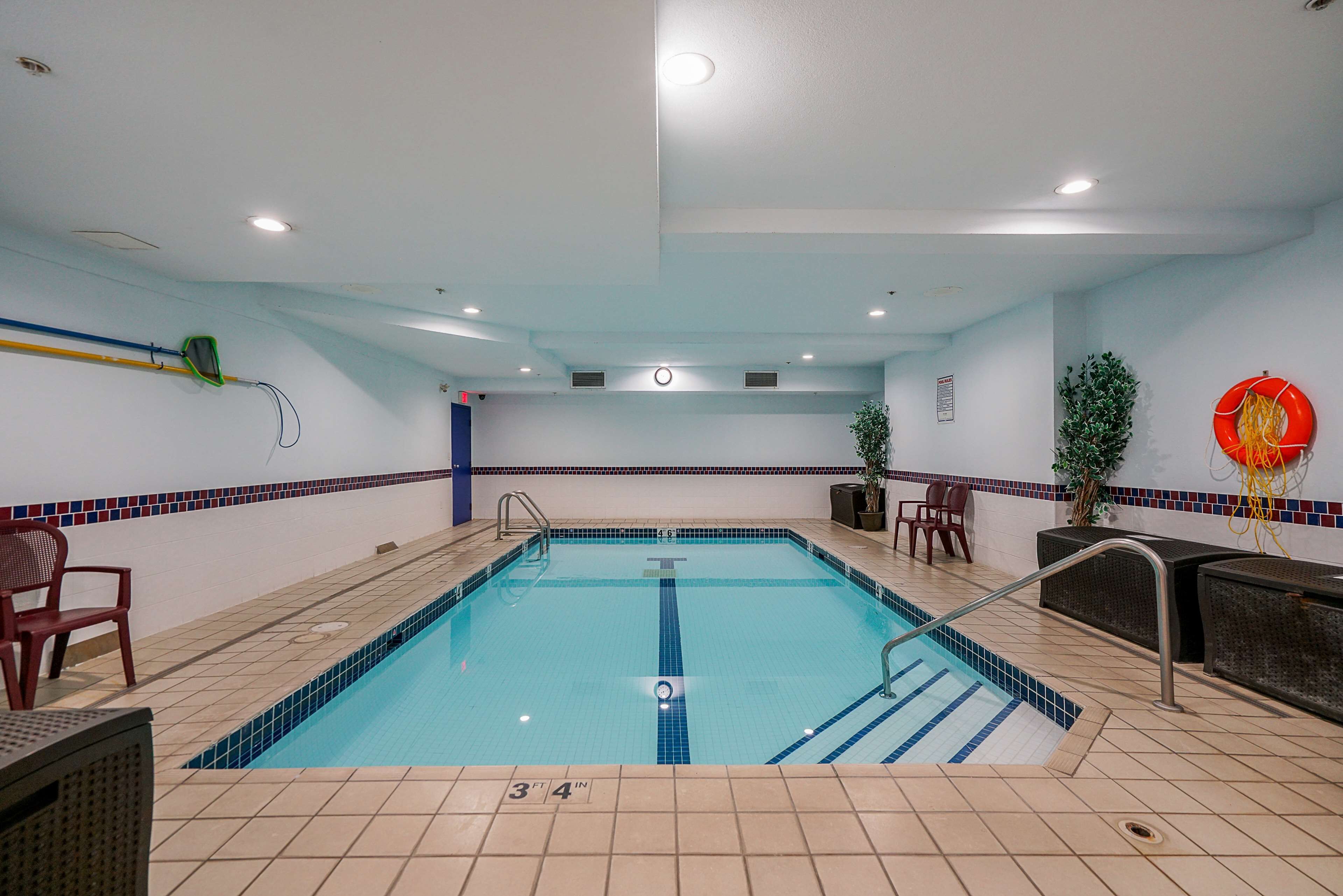 Una piscina interna con pavimento piastrellato, un galleggiante e alcuni sedili.