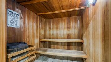 Una sauna con paredes de madera y suelo de baldosas, que incluye un letrero de advertencia sobre seguridad acuática.