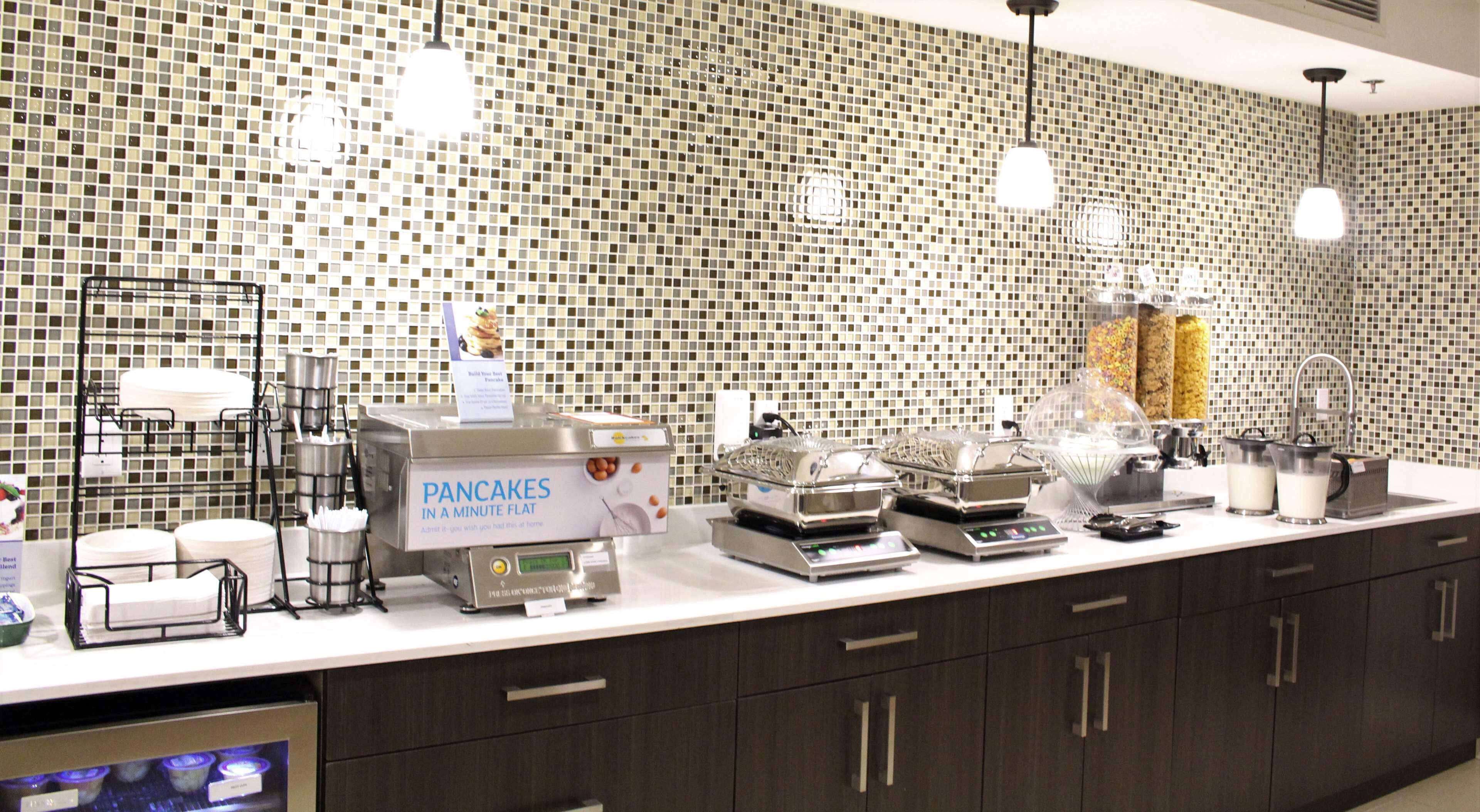 A breakfast station with a sign for pancakes, a coffee machine, and a milk dispenser.