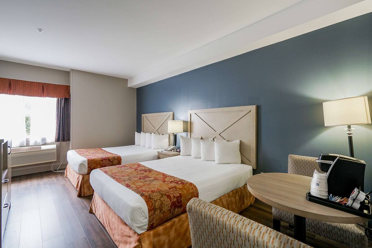 Une chambre d’hôtel avec deux lits, un bureau, une chaise et une table.