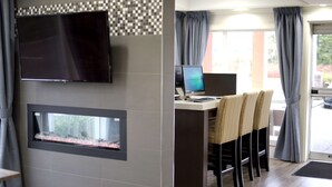 A modern room with a flat-screen TV mounted on the wall, a small aquarium, a desk with a laptop, and wicker chairs.