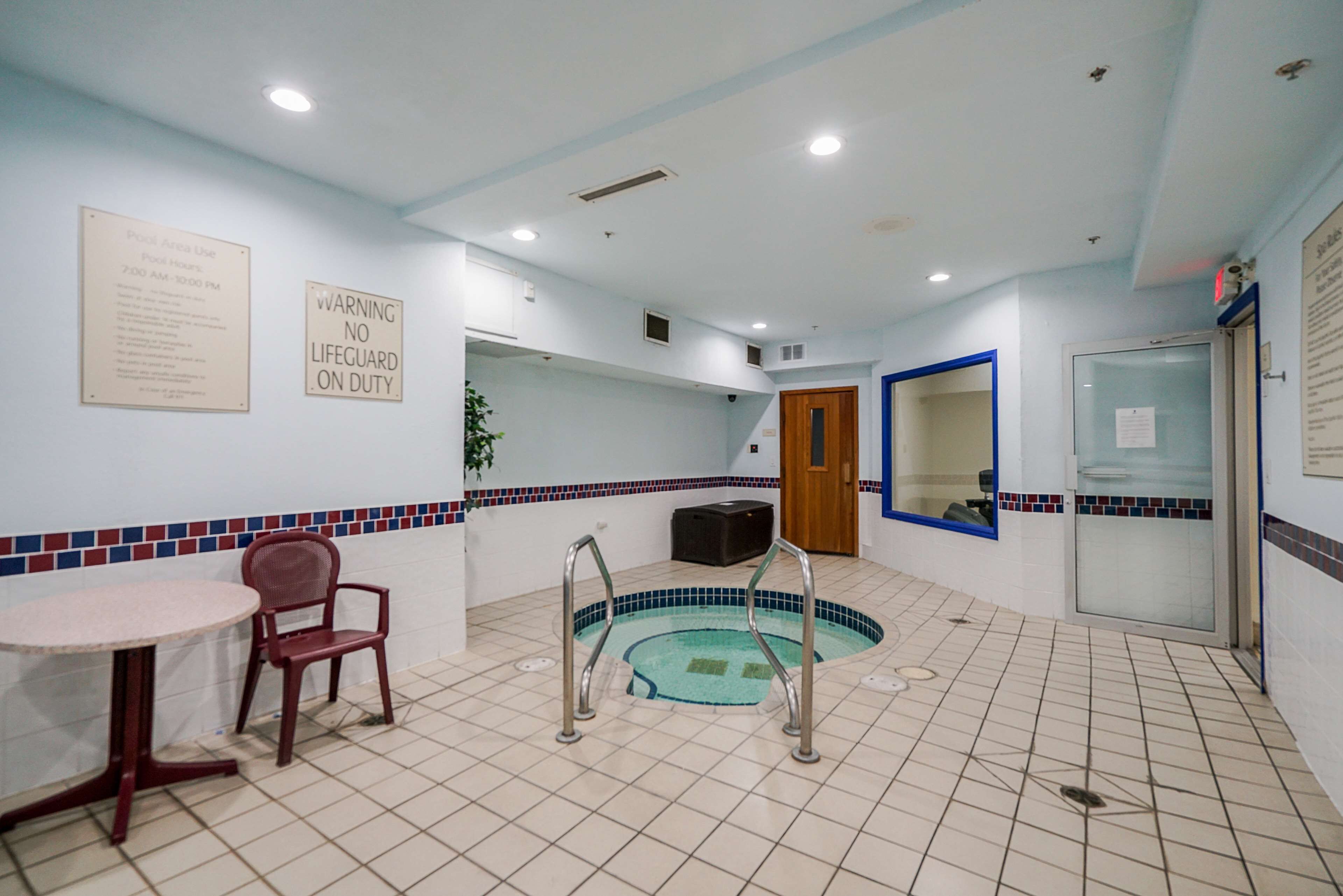 A pool area with a sign indicating no lifeguard on duty, a small table, and a chair.