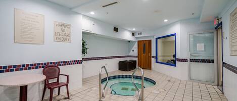 A pool area with a sign indicating no lifeguard on duty, a small table, and a chair.