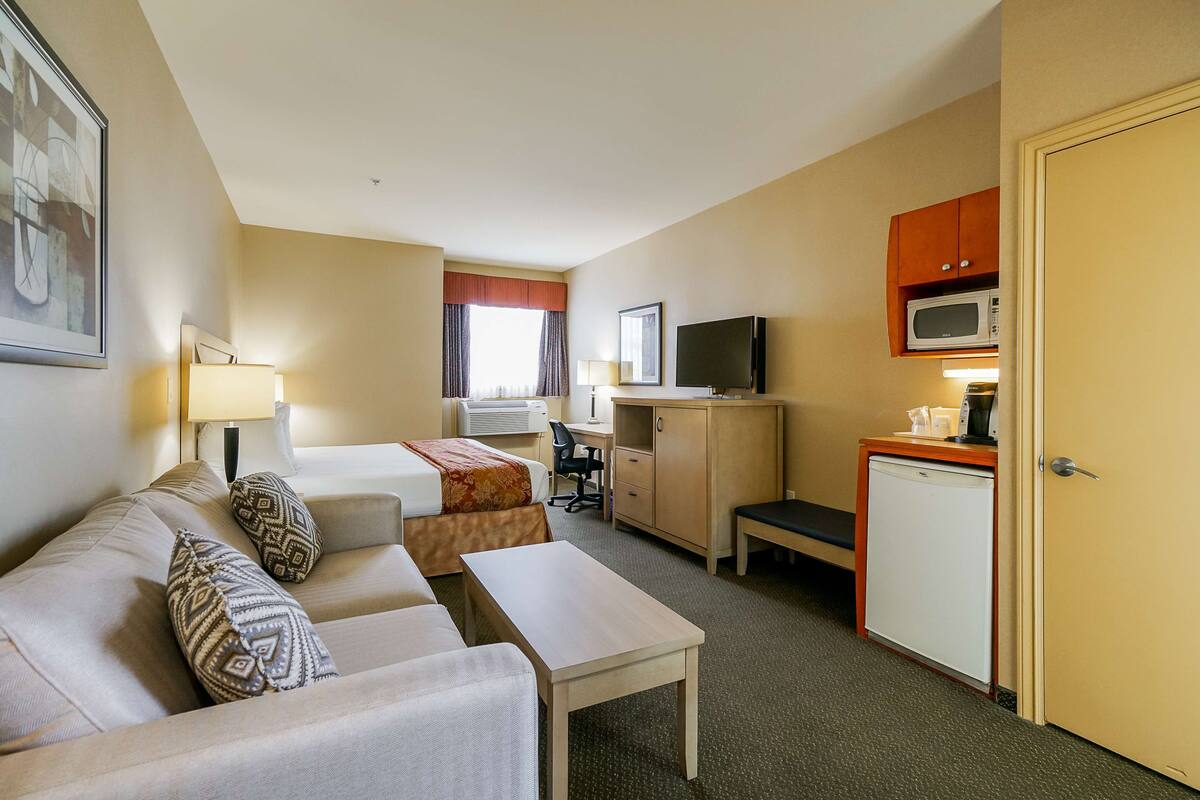 Une chambre d’hôtel équipée d’un lit, d’un canapé, d’un bureau, d’une télévision, d’un four à micro-ondes et d’une porte.