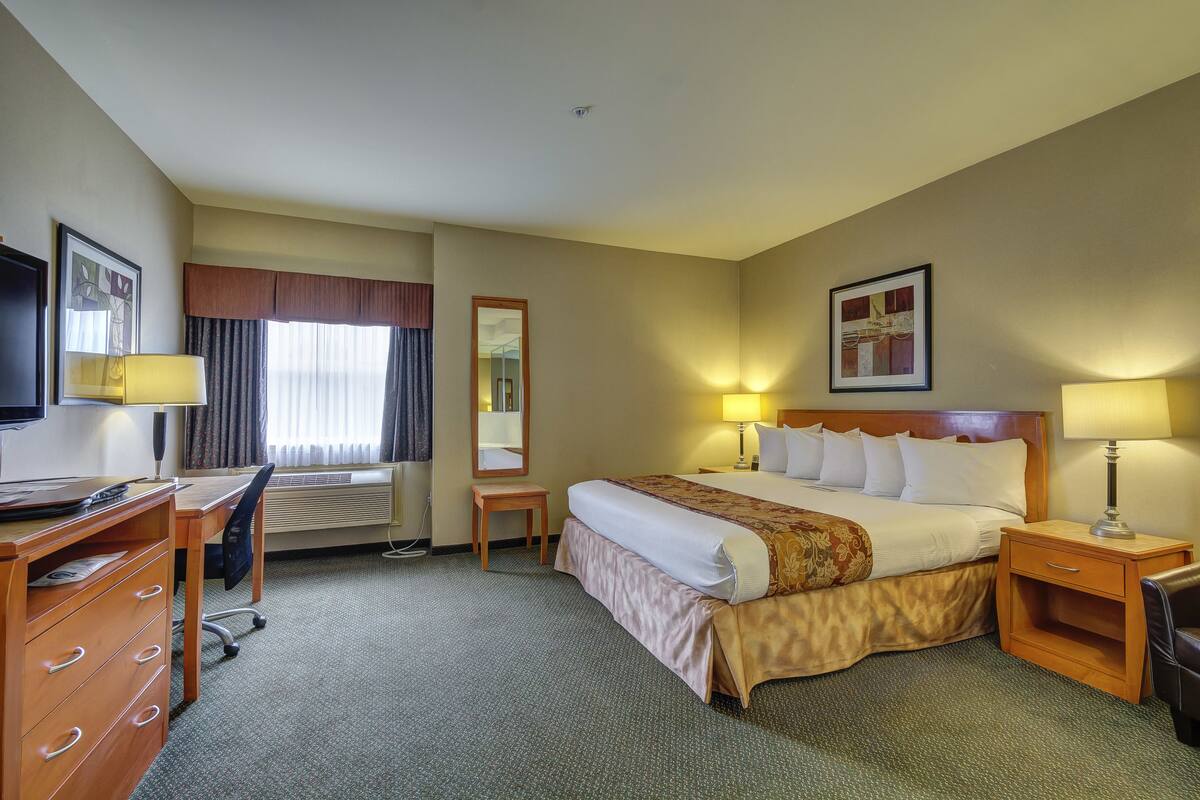 Une chambre d’hôtel équipée d’un lit, d’un bureau, d’une chaise, d’une télévision et de lampes.