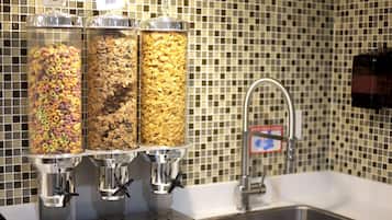 Una barra de desayuno con tres dispensadores de cereal y un lavamanos con grifo.
