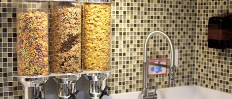 A breakfast bar with three cereal dispensers and a sink with a faucet.