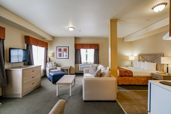 A hotel room with a bed, a sofa, a desk, a television, and a window with curtains. - Best Western Peace Arch Inn (Surrey)