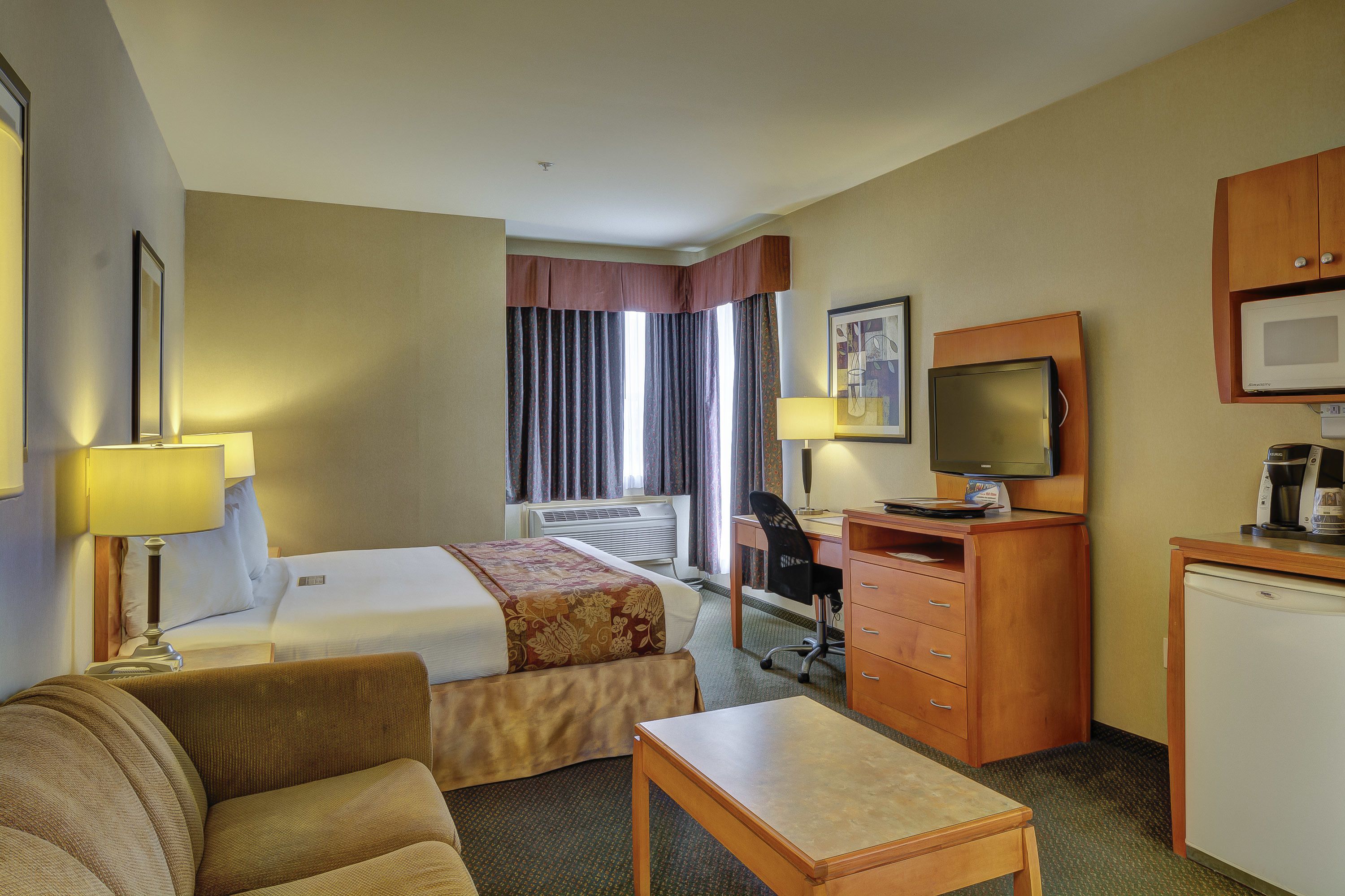 A hotel room with two beds, a desk, a television, a microwave, and a coffee maker.