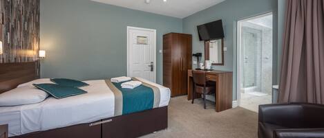 A hotel room with a bed, desk, chair, and a television.