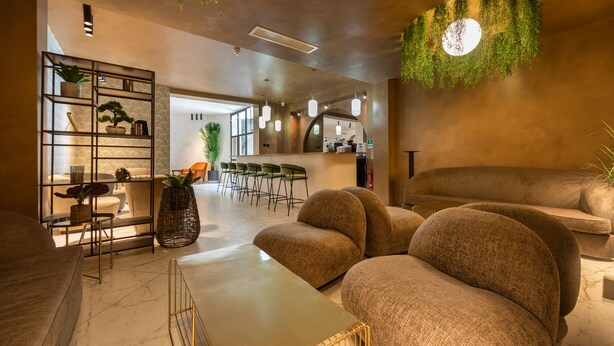 Un espace de détente moderne avec des canapés, une table basse, une bibliothèque et des plantes suspendues.