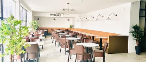 A spacious restaurant with high ceilings, marble flooring, and a variety of seating options including round tables and booths.