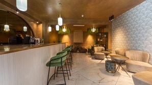 Un espace bar moderne doté d’un comptoir incurvé, de tabourets de bar verts et d’un coin salon avec des tables rondes et des chaises rembourrées.