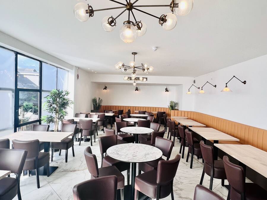 A modern dining area with round tables, dark chairs, and a unique chandelier.