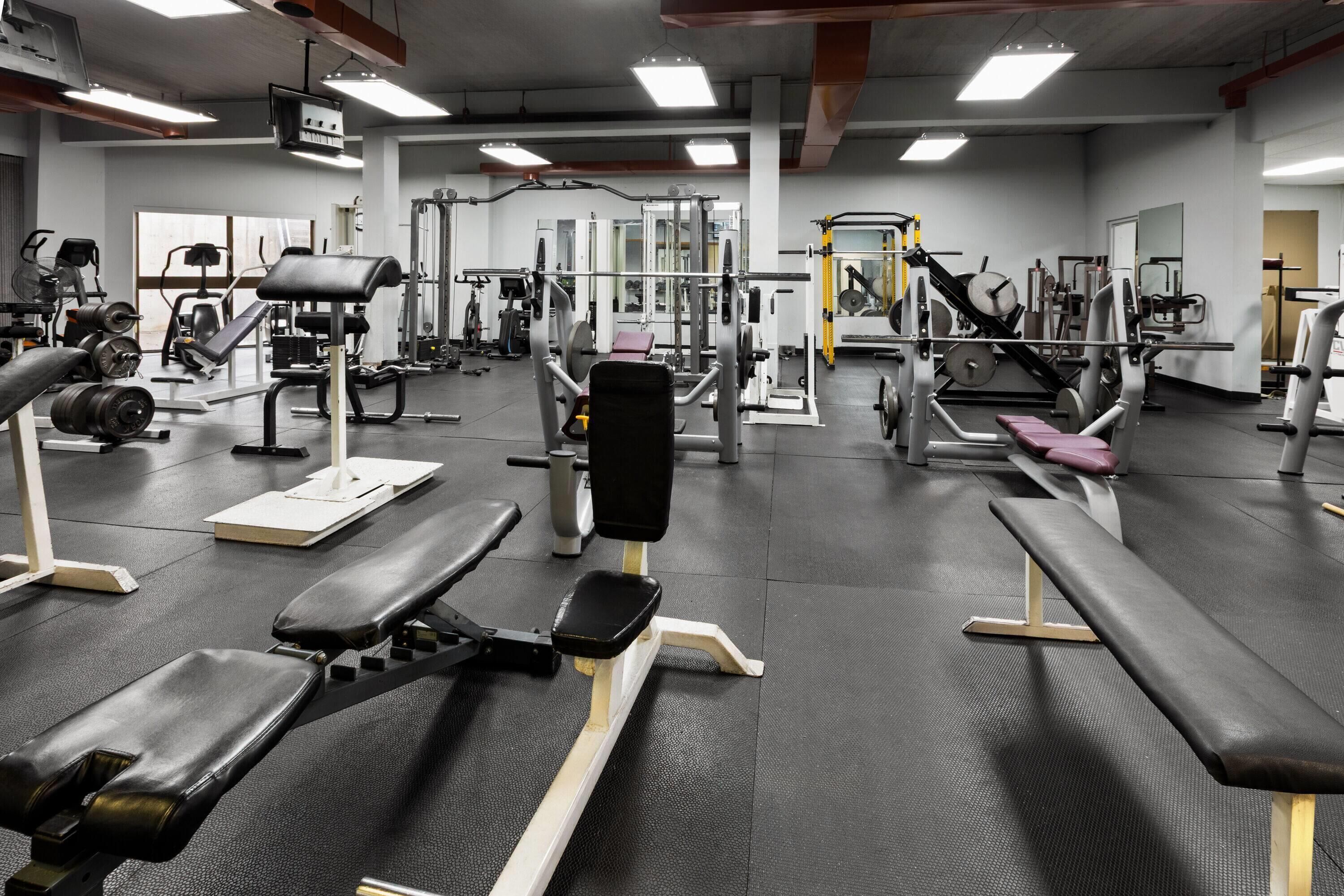 Une salle de sport équipée de divers appareils d’exercice, de bancs et de machines de musculation.