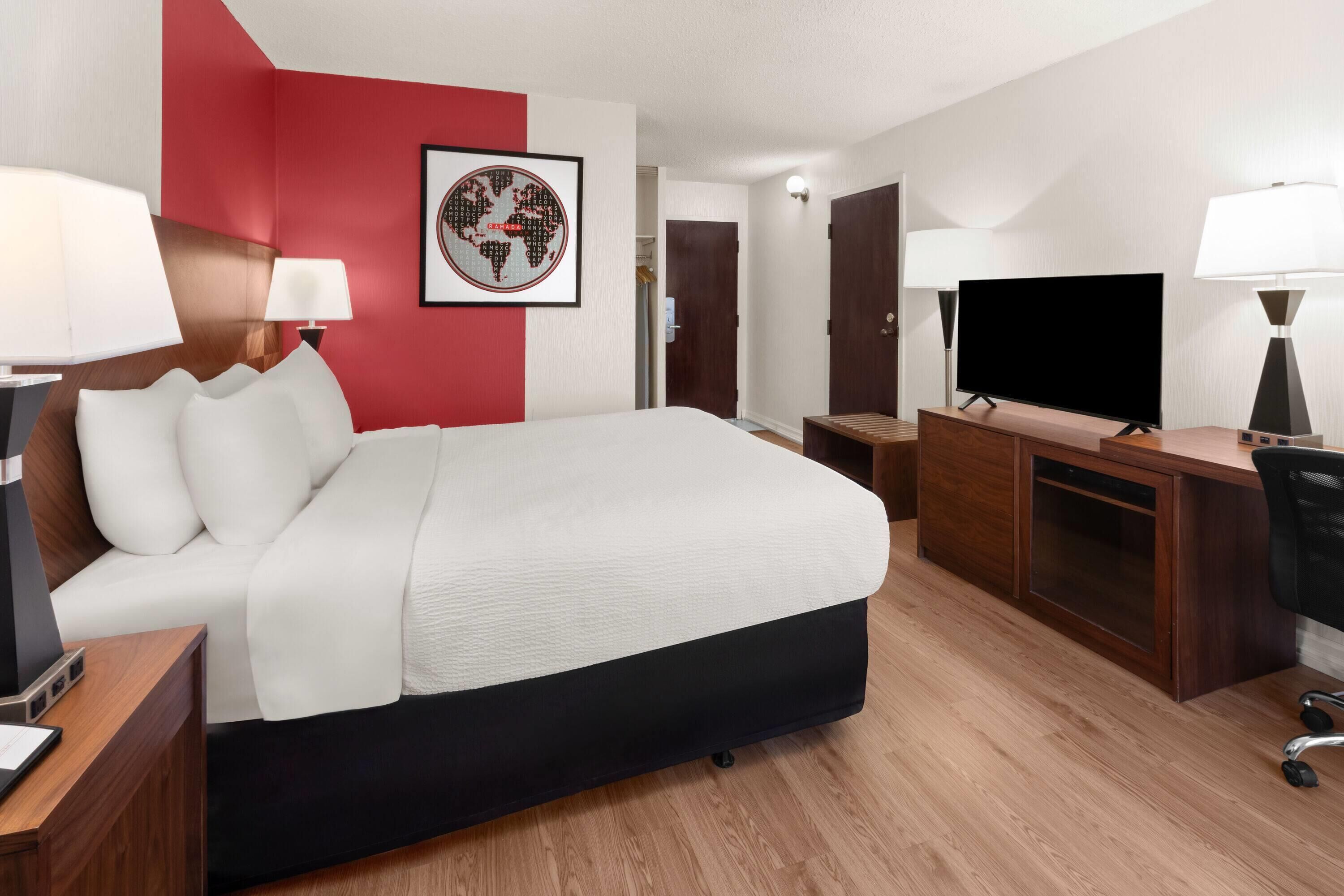 A hotel room with a bed, desk, TV, and lamps.