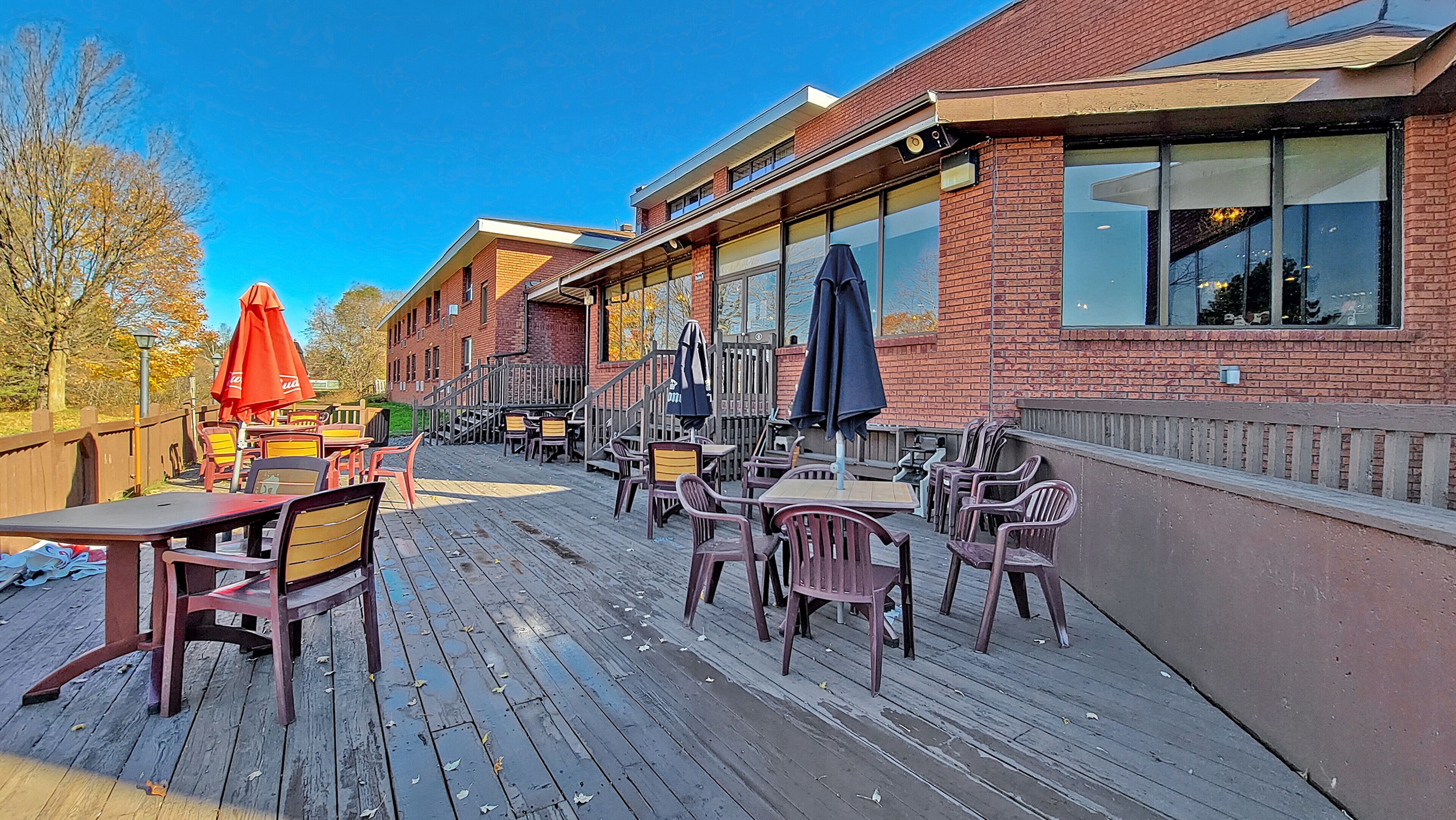 Une terrasse extérieure avec une plateforme en bois, des tables, des chaises et des parasols.