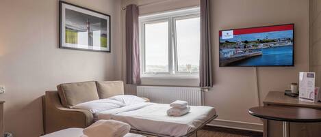 A hotel room with two beds, a TV, a framed picture, and a window with curtains.
