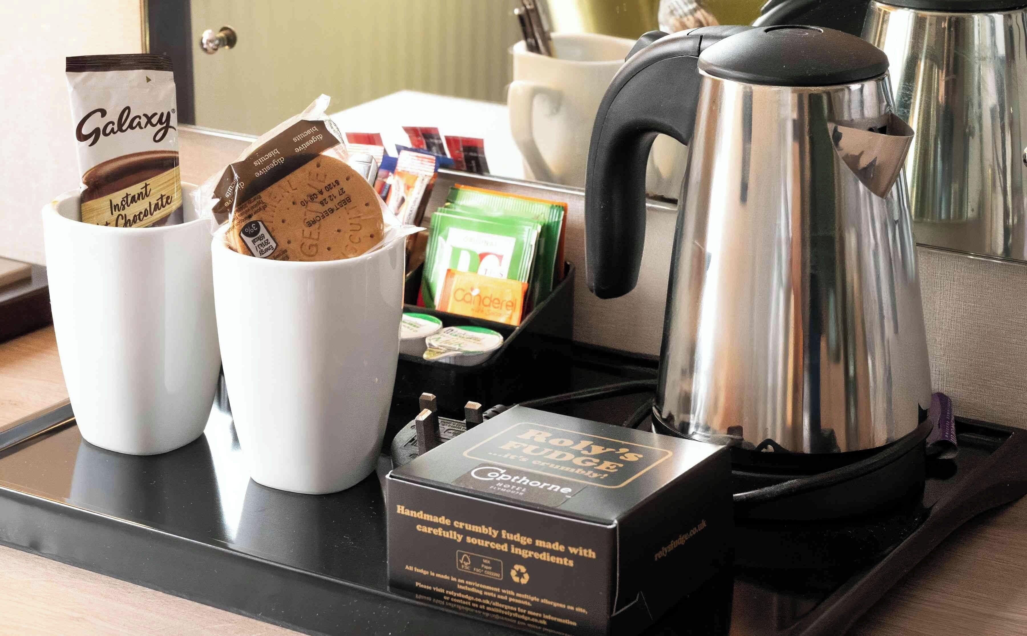 Ein Tablett mit einer Kaffeemaschine, zwei Tassen, einer Packung Galaxy Instant-Schokolade und einer Packung Royale Fudge.