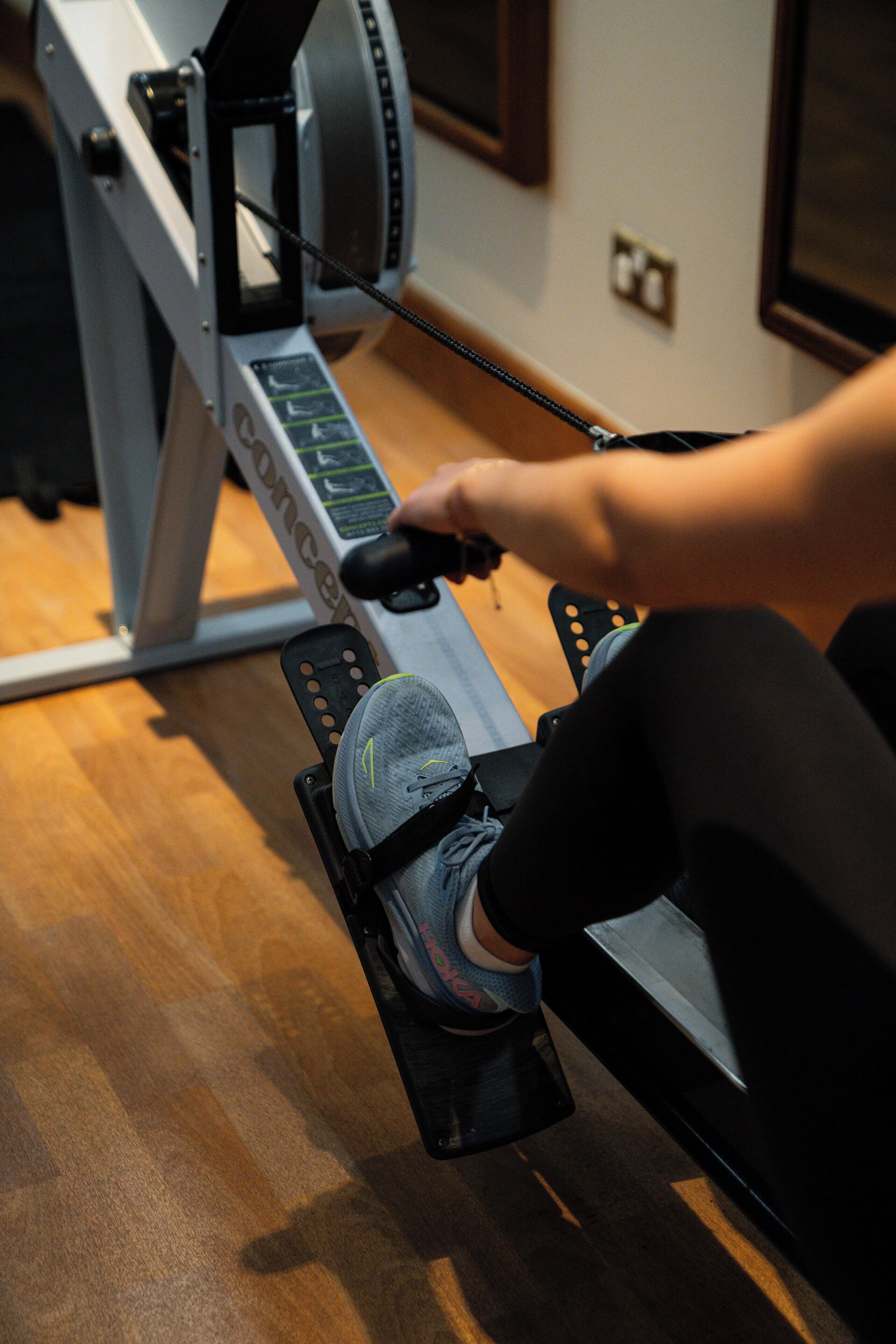 A rowing machine in a gym with a wooden floor.