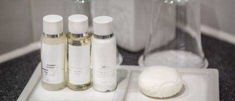 Ein Badezimmer-Waschtisch mit drei Flaschen Shampoo und Conditioner, einer Glasflasche und einer Seife.