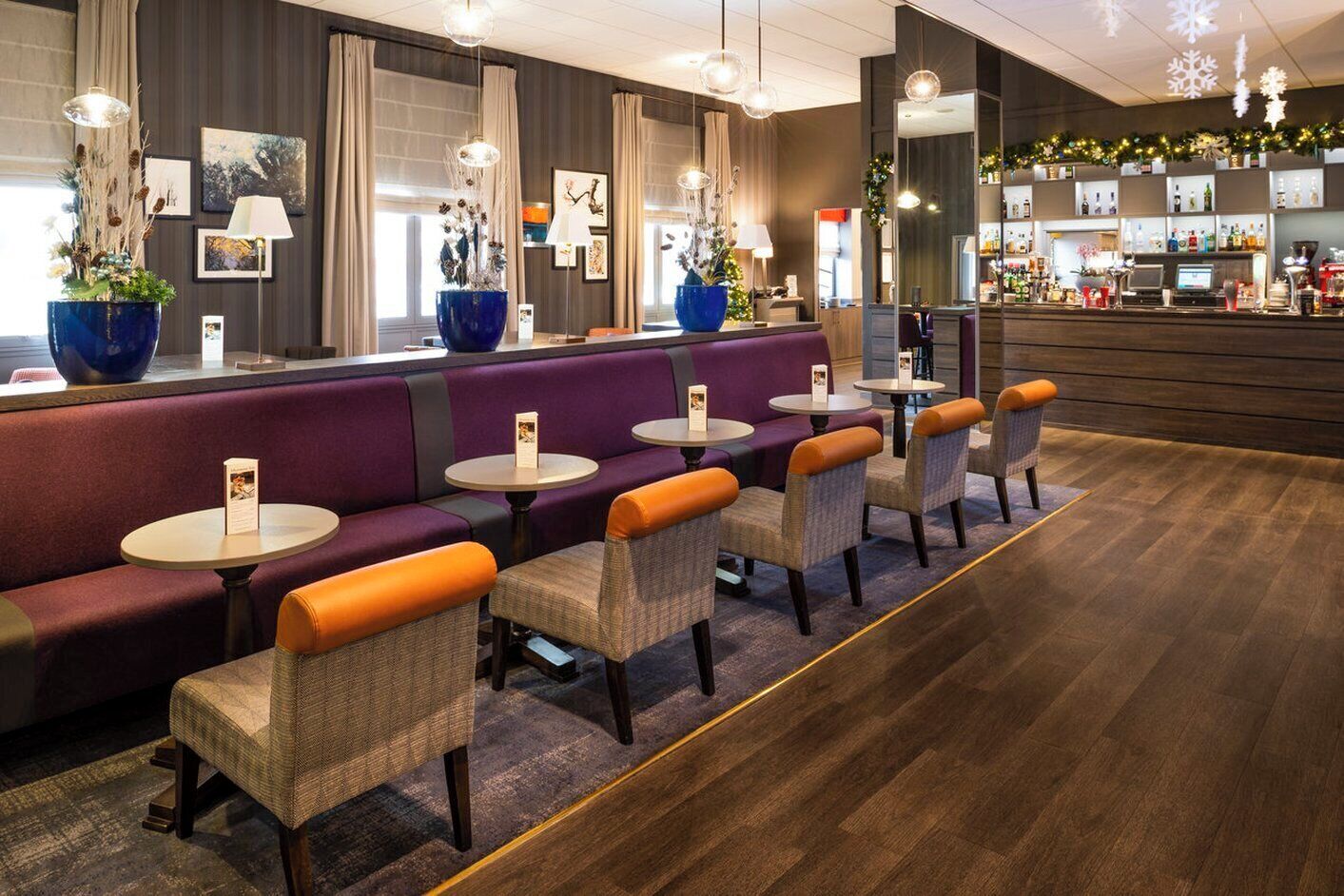 Un espace bar moderne doté de sièges, notamment un comptoir, des fauteuils confortables et des tables rondes.