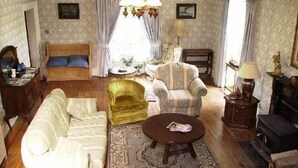 A traditional living room with a sofa, armchair, and a small round table. - Clanabogan Country House B&B (Omagh)