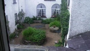 A courtyard with a white building, two arched windows, and a brick pathway. - Clanabogan Country House B&B (Omagh)