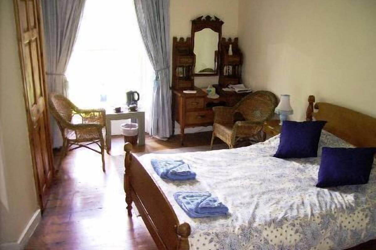 Un dormitorio con cama, cómoda, silla y escritorio.