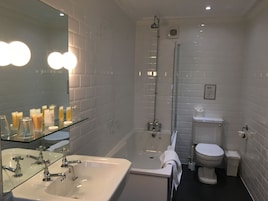 A modern bathroom with a glass shower enclosure, a white sink with chrome fixtures, and a toilet with a paper towel dispenser.