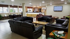 A hotel lobby with leather sofas, a coffee table, a reception desk, and a TV screen. - Skylark Hotel (Southend-on-Sea)