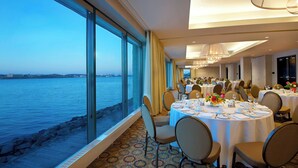 A dining area with round tables, chairs, and a view of the water.