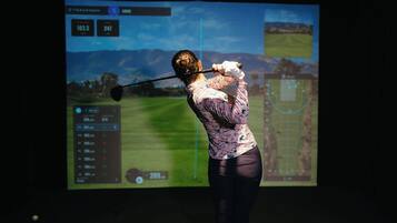 A person playing golf with a screen displaying a golf course and statistics.