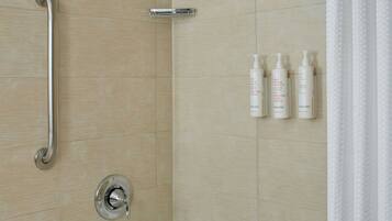 A modern bathroom with a bathtub, a shower with a handheld showerhead, a grab bar, and a set of toiletries on the wall.