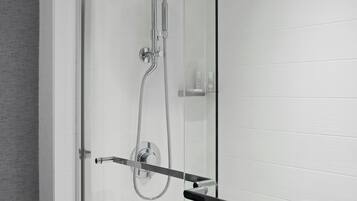 A modern shower with a glass enclosure, a handheld showerhead, and a towel rack.