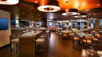 A spacious restaurant with multiple dining areas, a bar, and a kitchen visible in the background.